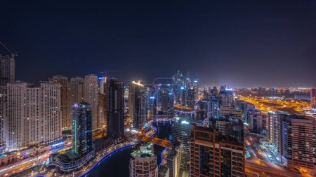 Photo for Panorama of various skyscrapers in tallest recidential block in Dubai Marina aerial during all night timelapse with artificial canal. Many towers and yachts - Royalty Free Image