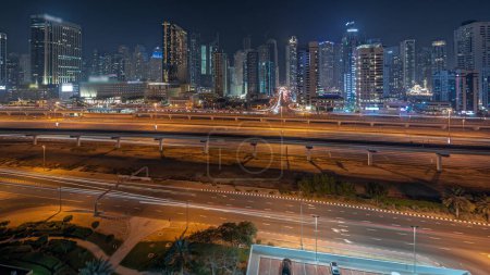 Téléchargez les photos : Panorama montrant Dubai Marina plus haut bloc de gratte-ciel timelapse de nuit. Vue aérienne du quartier JLT vers les immeubles à appartements, les hôtels et les tours de bureaux près de l'autoroute. - en image libre de droit