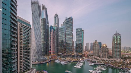 Photo for Dubai marina tallest skyscrapers and yachts in harbor aerial panoramic after sunset. View at apartment buildings, hotels and office blocks, modern residential development of UAE - Royalty Free Image