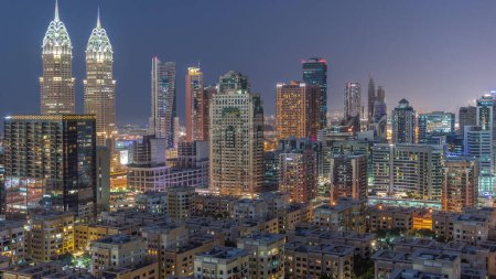 Téléchargez les photos : Des gratte-ciels dans le quartier de Barsha Heights et des immeubles de faible hauteur dans le quartier des Verts transition aérienne de jour à nuit. Skyline de Dubaï avec des tours de ville internet - en image libre de droit