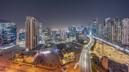 Téléchargez les photos : Business Bay with modern towers residential development aerial panoramic day to night transition , Dubai, UAE. Skyscrapers with traffic on a road near big parking lot after sunset - en image libre de droit
