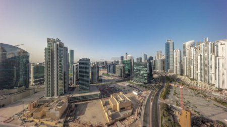 Foto de Bay Avenue con torres modernas desarrollo residencial en Business Bay panorámica aérea durante el amanecer, Dubai, Emiratos Árabes Unidos. Rascacielos con tráfico en una carretera cerca de un gran aparcamiento - Imagen libre de derechos