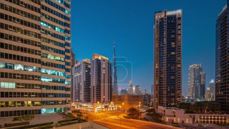 Téléchargez les photos : Vue panoramique aérienne du centre-ville de Dubaï et des gratte-ciel difc avec un trafic achalandé à l'intersection dans le quartier de Business Bay transition jour-nuit après le coucher du soleil. - en image libre de droit