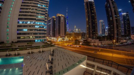 Téléchargez les photos : Panorama aérien du centre-ville de Dubaï et des gratte-ciel difc avec un trafic achalandé à l'intersection dans le quartier de Business bay transition jour-nuit . - en image libre de droit