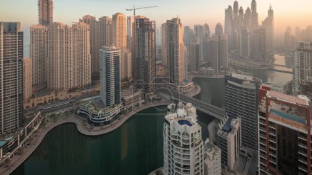 Foto de View of various skyscrapers in tallest recidential block in Dubai Marina and JBR district aerial night to day transition  with artificial canal. Many towers and yachts during sunrise - Imagen libre de derechos