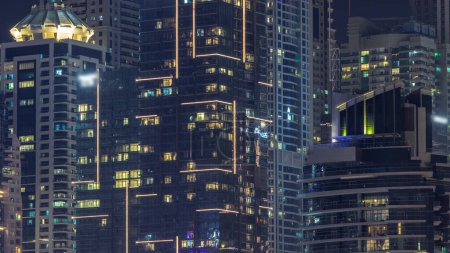 Foto de Vista nocturna de luces en ventanas panorámicas de edificios de varios pisos aéreos. Rascacielos iluminado en una gran ciudad - Imagen libre de derechos