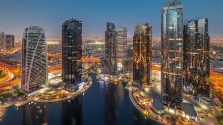 Téléchargez les photos : Bâtiments résidentiels hauts du quartier JLT transition aérienne du jour à la nuit panoramique, faisant partie du quartier mixte du centre multi-commodités de Dubaï. Villa maisons sur un fond - en image libre de droit