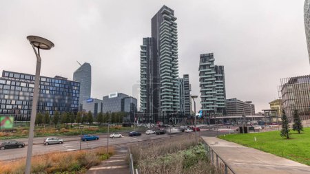 Photo for Panorama showing skyscrapers and biblioteca from park with green lawn timelapse. Located between Piazza Gae Aulenti and the Isola district. Traffic on the road intersection. Milan. Italy - Royalty Free Image