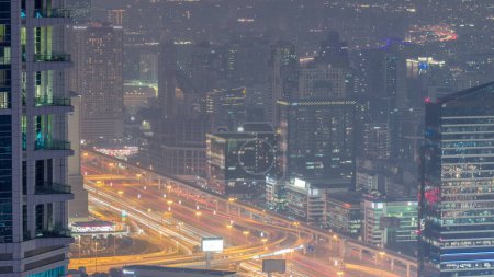 Téléchargez les photos : Dubai Vue aérienne montrant al barsha hauteurs et verdure quartier zone jour à nuit transition de la marina de Dubaï. Tours et gratte-ciel avec circulation sur une autoroute d'en haut après le coucher du soleil - en image libre de droit