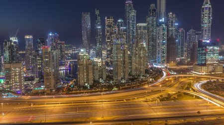 Photo for Skyscrapers of Dubai Marina with illuminated highest residential buildings day to night transition after sunset with traffic on a highway. Aerial top view from JLT district - Royalty Free Image