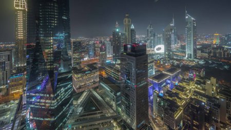 Foto de Panorama mostrando rascacielos futuristas en el centro de negocios del distrito financiero en Dubai en la noche de camino Sheikh Zayed. Vista aérea desde arriba con torres iluminadas - Imagen libre de derechos
