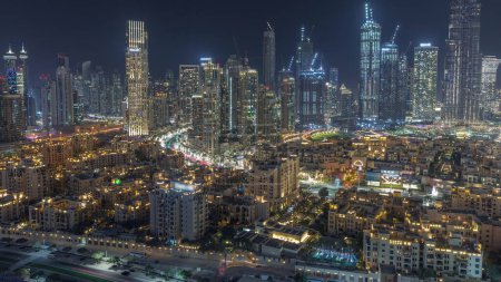 Téléchargez les photos : Vue rapprochée sur les tours de la baie d'affaires de Dubaï transition aérienne de jour à nuit. Vue sur le toit de certains gratte-ciel et de nouvelles tours en construction après le coucher du soleil - en image libre de droit