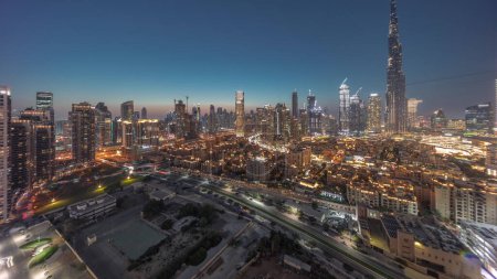 Foto de Dubai Downtown day to night transition with tallest skyscraper and other towers panoramic view from the top during sunset in Dubai, United Arab Emirates. Lights turning on. - Imagen libre de derechos