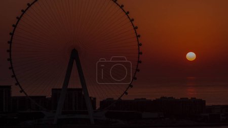 Téléchargez les photos : Sunset over Bluewaters island with modern architecture and ferris wheel aerial close up view. New leisure and residential area near Dubai marina and JBR. Orange sky - en image libre de droit