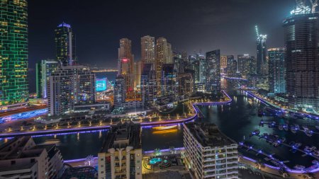 Photo for Panorama showing Dubai Marina skyscrapers and JBR district with luxury buildings and resorts aerial night. Illuminated waterfront and boats floating in canal - Royalty Free Image