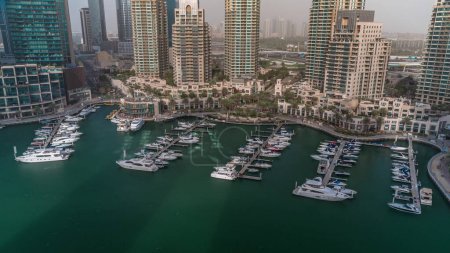 Téléchargez les photos : Bateaux de luxe et yachts amarrés à Dubai Marina Aerial toute la journée avec des ombres se déplaçant rapidement. Bateaux à moteur garés le long de la jetée dans le port près du front de mer - en image libre de droit