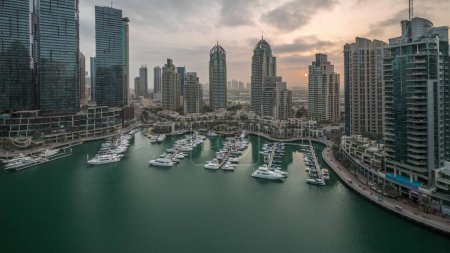 Foto de Luxury yacht bay in the city aerial night to day transition in Dubai marina panorama before sunrise. Modern skyscrapers along waterfront promenade and boats floating in harbor - Imagen libre de derechos