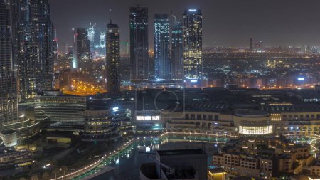 Photo for Dubai downtown with fountains and modern futuristic architecture aerial during all night. View to skyscrapers under construction with shopping mall. Lights turning off - Royalty Free Image