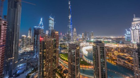 Foto de Panorama del paisaje urbano del centro de Dubái con rascacielos más altos alrededor de la transición aérea día a noche. Sitio de construcción de nuevas torres y carreteras ocupadas con tráfico desde arriba - Imagen libre de derechos
