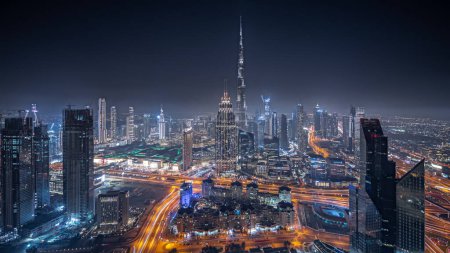 Foto de Panorama showing aerial view of tallest towers in Dubai Downtown skyline and highway night panorama. Financial district and business area in smart urban city. Skyscraper and high-rise buildings - Imagen libre de derechos