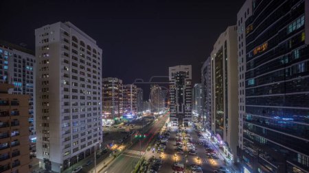 Foto de Edificios residenciales y arquitectura moderna de la ciudad de Abu Dhabi timelapse aéreo durante toda la noche hasta el amanecer, Emiratos Árabes Unidos. Vista desde arriba a los coches en el estacionamiento y largas sombras de torres con rascacielos - Imagen libre de derechos