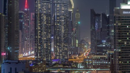 Téléchargez les photos : Tours futuristes et gratte-ciel éclairés avec circulation dans les rues de Dubaï Centre-ville et quartier financier. Urbain ville skyline aérienne nuit timelapse. Fenêtres éclatantes - en image libre de droit