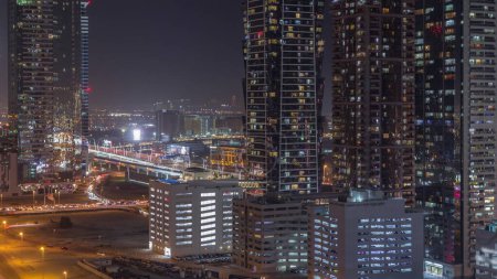 Téléchargez les photos : Business Bay skyline de quartier avec l'architecture moderne timelapse nuit d'en haut. Vue aérienne des gratte-ciel de Dubaï et des tours éclairées avec des fenêtres éclatantes près de l'autoroute principale. Trafic au carrefour - en image libre de droit