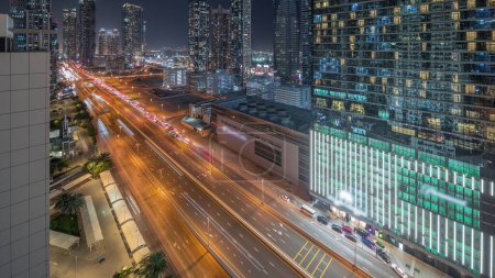 Photo for Business bay district panoramic skyline with modern architecture timelapse night from above. Aerial view of Dubai skyscrapers and illuminated towers near main highway. Traffic on a crossroad - Royalty Free Image