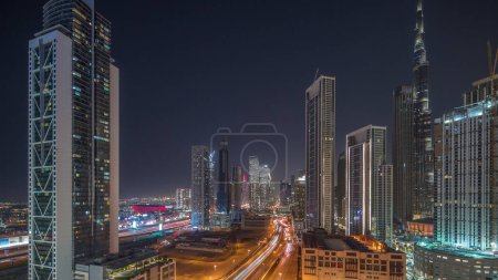 Foto de Vista aérea del horizonte del centro de Dubái con muchas torres iluminadas más altas de noche timelapse. Área de negocios en la ciudad urbana inteligente. Rascacielos y edificios de gran altura desde arriba, Emiratos Árabes Unidos. - Imagen libre de derechos