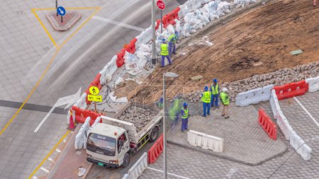 Photo for Process of sidewalk road repairing with many builder workers and equipment breaking pavement and concrete. Loading in cargo truck at construction site. Aerial timelapse of new walkway works in Dubai - Royalty Free Image