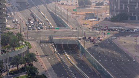Photo for Top aerial view of busy road intersection and traffic junctions in Dubai city timelapse. Modern construction design of crossroads and highways to avoid traffic jams. Many driving cars at morning haze - Royalty Free Image