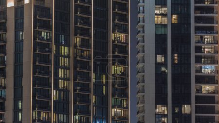 Foto de Grandes bloques de pisos con ventanas brillantes ubicados en el distrito residencial de la ciudad timelapse aéreo. Luz nocturna en apartamentos en torres y rascacielos - Imagen libre de derechos