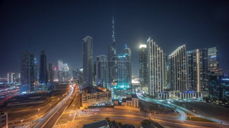 Photo for Aerial panoramic view of Dubai Downtown skyline with many illuminated towers night timelapse. Road traffic in urban city. Skyscraper and high-rise buildings with turning off light from above, UAE. - Royalty Free Image