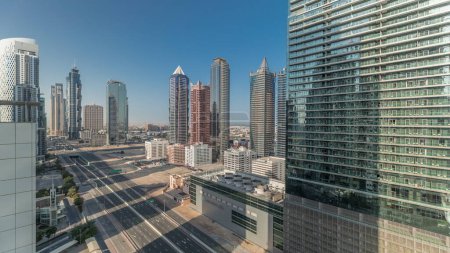 Téléchargez les photos : Panorama montrant le quartier de la baie d'affaires et l'horizon du centre-ville avec une architecture moderne timelapse d'en haut. Vue aérienne des gratte-ciel et des tours de Dubaï près de l'autoroute principale. Trafic au carrefour - en image libre de droit