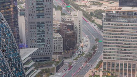 Foto de Vista aérea del tráfico en la calle Al Saada en el distrito financiero día a noche timelapse transición en Dubai, Emiratos Árabes Unidos. Rascacielos iluminados y ventanas brillantes en torres de oficinas desde arriba. - Imagen libre de derechos