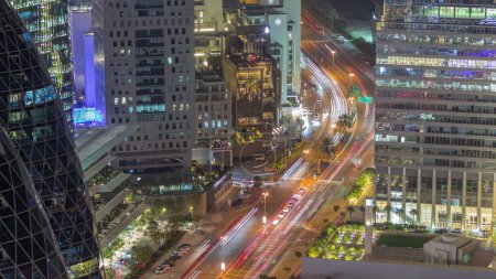 Téléchargez les photos : Vue aérienne de la circulation sur la rue Al Saada dans le quartier financier de nuit timelapse à Dubaï, EAU. gratte-ciel éclairés et fenêtres incandescentes dans les tours de bureaux d'en haut. - en image libre de droit