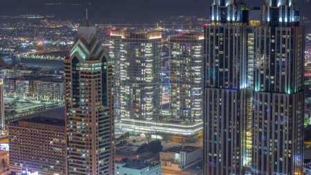 Foto de Edificios de gran altura en Sheikh Zayed Road en Dubai aerial night timelapse, EAU. Rascacielos en el distrito financiero internacional desde arriba. Casas de paseo por la ciudad y villas en un fondo - Imagen libre de derechos