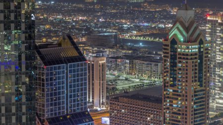 Foto de Edificios de gran altura en Sheikh Zayed Road en Dubai aerial night timelapse, EAU. Paseo por la ciudad casas y villas en un fondo. Rascacielos en el distrito financiero internacional desde arriba. - Imagen libre de derechos
