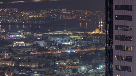 Téléchargez les photos : Vue aérienne des maisons d'appartements et villas dans la ville de Dubaï près du timelapse nocturne du centre-ville. Mosquée éclairée derrière le gratte-ciel. Émirats arabes unis - en image libre de droit