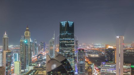 Téléchargez les photos : Vue aérienne des immeubles de grande hauteur sur Sheikh Zayed Road à Dubaï timelapse de nuit aérienne, Émirats arabes unis. Des gratte-ciel éclairés de la place financière internationale. Circulation nocturne - en image libre de droit