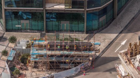 Téléchargez les photos : Beaucoup de travailleurs sur le chantier de construction faisant cadre métallique d'armature pour le béton coulant timelapse aérienne. Construction d'un nouveau pont reliant les gratte-ciel. Dubaï - en image libre de droit