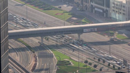 Foto de Vista aérea desde arriba a una concurrida intersección de carreteras en Dubai timelapse centro. Coches coloridos y camiones que conducen en ambas direcciones en la carretera sheikh zayed. Atasco de tráfico en la hora punta de la noche - Imagen libre de derechos