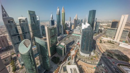 Foto de Vista del horizonte de los edificios de gran altura en Sheikh Zayed Road en Dubai timelapse aéreo durante la puesta del sol, Emiratos Árabes Unidos. Rascacielos con largas sombras en el centro financiero del Centro Financiero Internacional desde arriba - Imagen libre de derechos