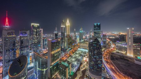 Photo for Skyline panoramic view of the high-rise buildings on Sheikh Zayed Road in Dubai aerial night timelapse, UAE. Illuminated skyscrapers in International Financial Centre near shopping avenue from above - Royalty Free Image