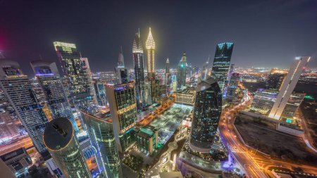Téléchargez les photos : Skyline vue panoramique vers le bas des immeubles de grande hauteur sur Sheikh Zayed Road à Dubaï timelapse de nuit aérienne, Émirats arabes unis. Des gratte-ciel éclairés de la place financière internationale d'en haut - en image libre de droit