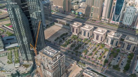 Téléchargez les photos : Site de construction avec grues et bâtiments sur Sheikh Zayed Road à Dubaï timelapse aérien, EAU. Gratte-ciel dans le quartier financier d'en haut avec de longues ombres mouvantes. Parking avec beaucoup de voitures - en image libre de droit