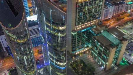 Téléchargez les photos : Vue en bas des immeubles de grande hauteur sur Sheikh Zayed Road à Dubaï timelapse de nuit aérienne, Émirats arabes unis. Des gratte-ciel éclairés avec des fenêtres éclatantes dans le Centre financier international d'en haut - en image libre de droit