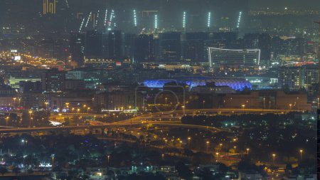 Foto de Bur Dubai y Deira distritos de la noche aérea timelapse visto desde el distrito financiero. Edificios ubicados a lo largo de Dubai Creek. Sitio de construcción detrás del estadio - Imagen libre de derechos