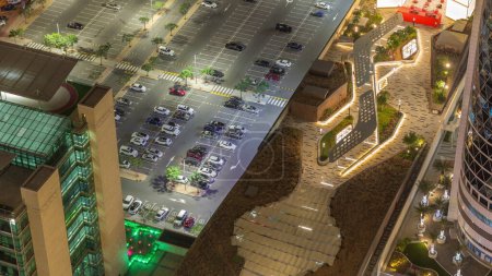 Foto de Vista aérea de muchos coches de colores estacionados en el estacionamiento con líneas y marcas para lugares de estacionamiento y direcciones de la noche timelapse. Dubai distrito financiero cerca de la avenida comercial a pie zona - Imagen libre de derechos