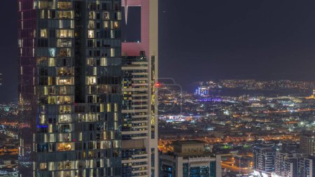 Téléchargez les photos : Vue aérienne des maisons d'appartements et villas dans la ville de Dubaï près du timelapse nocturne du centre-ville. Fenêtres clignotantes de gratte-ciel dans le quartier financier. Émirats arabes unis - en image libre de droit